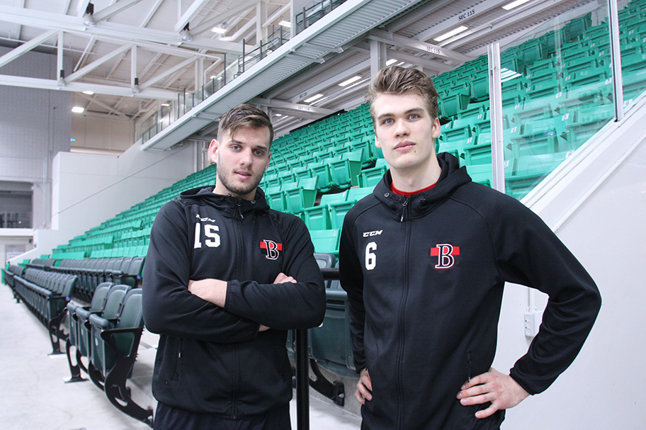Photo of two hockey players dressed in their black sweat suits.