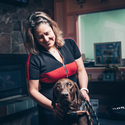 A veterinarian standing in a dark room holding a brown Labrador retriever.